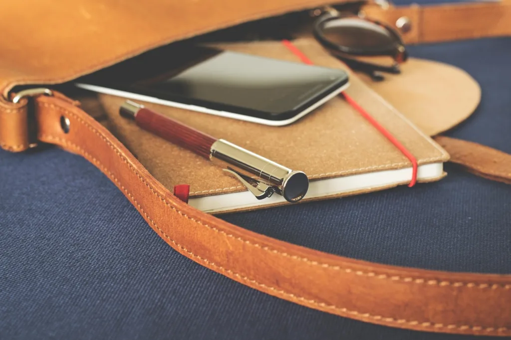 Smartphone en una mochila de trabajo junto a un bolígrafo y una agenda, simbolizando productividad para PYMEs