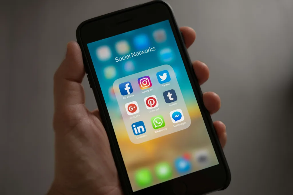 Mano sosteniendo un móvil con iconos de redes sociales en la pantalla, estrategia digital para PYMEs en Madrid
