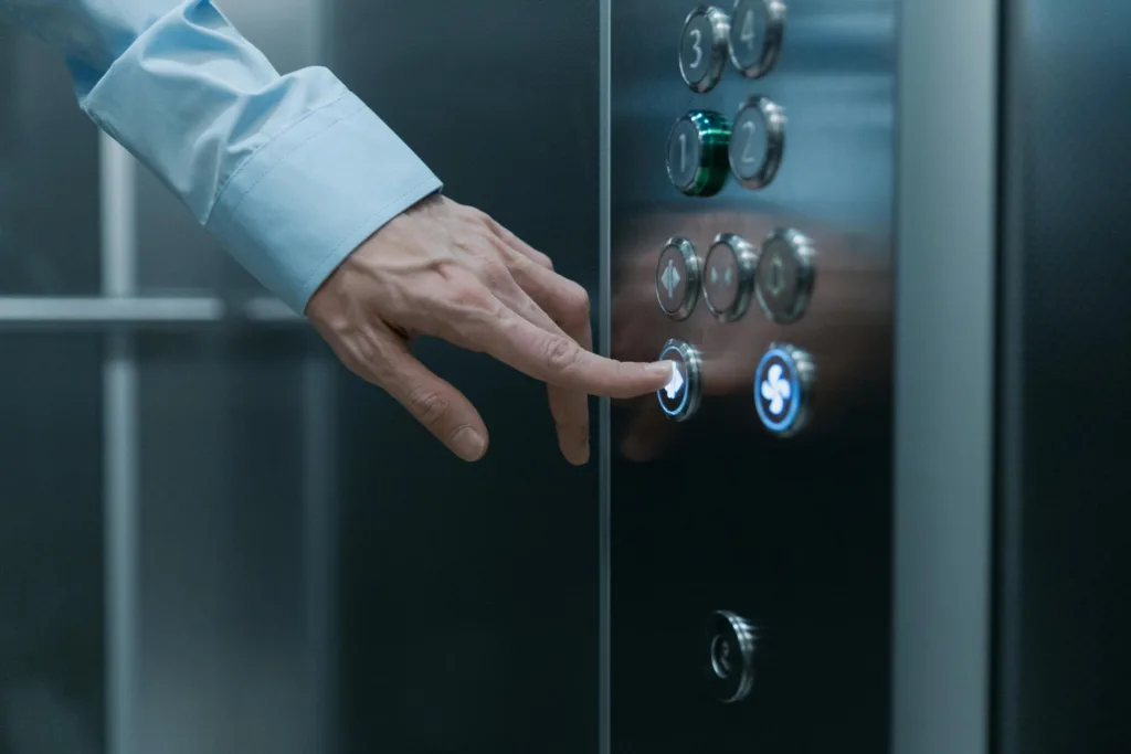 Mano de empresario pulsando un botón de ascensor como metáfora de un elevator pitch